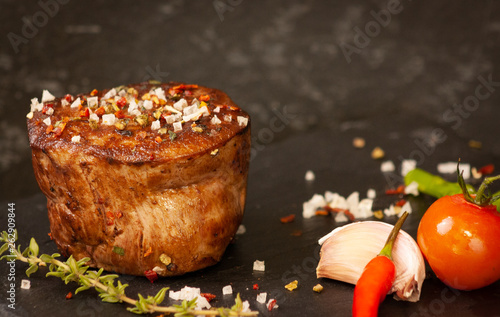 Delicious grilled filet of beef with tomatoes, chili pepper, garlig and thyme  on stone plate. photo