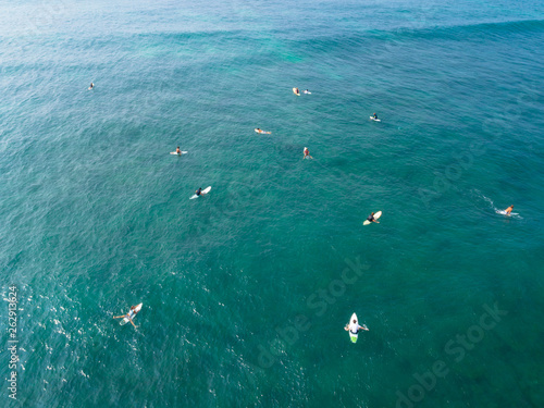 Aerial view from drone of surfers paddling for catching waves during surfing in the indian ocean