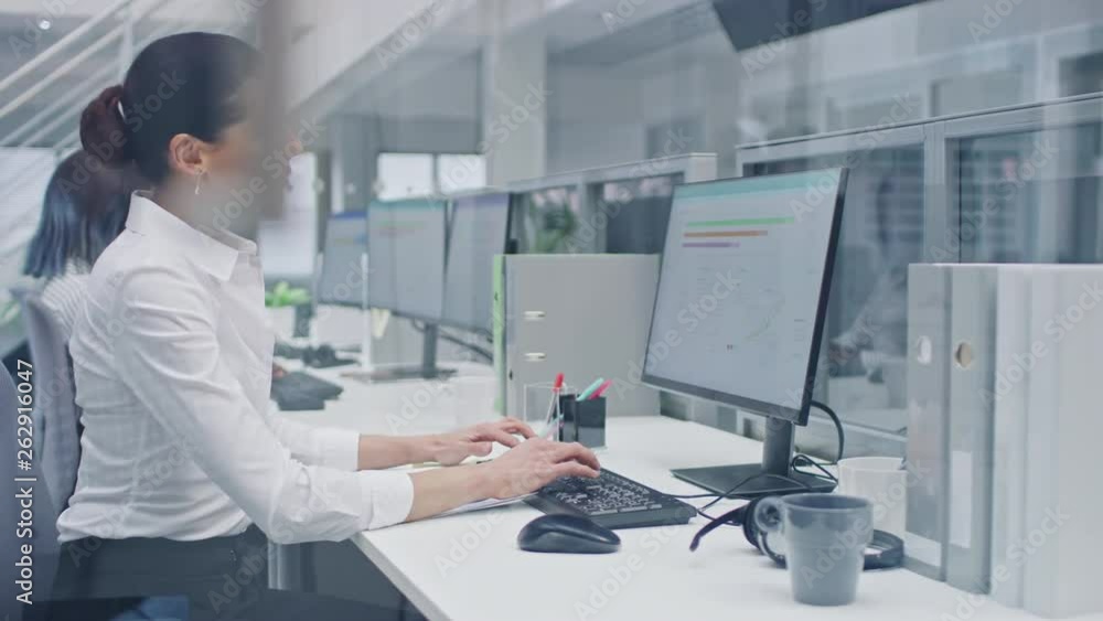 Beautiful Female Manager Works on a Desktop Computer and Compares Data on a Sheet of Paper. Diverse and Motivated Business People Work on Computers in Modern Open Office. Beautiful Female Manager Works on a Desktop Computer and Compares Data on a Sheet of Paper. Diverse and Motivated Business People Work on Computers in Modern Open Office.
