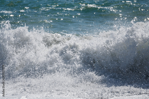 Waves and splashes of water against the sea on a sunny summer day