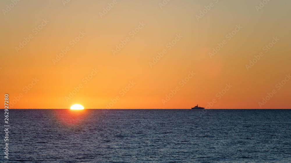 Orange sunset over the sea. The sun hides behind the horizon in the sea.