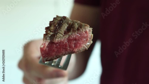 Taking a yummy perfectly grilled medium filet mignon steak slice on a fork - Close-up - Eating a paleo diet lunch photo