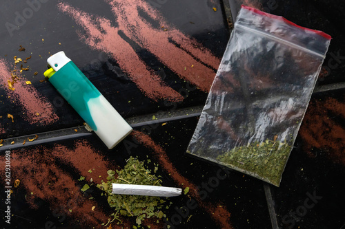 narcotic cigarette, lighter and a package of weeds on the table, short focus, toning