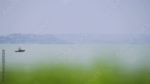 Afternoon landscape footage with a little boat which moving horizontally near the shore of Zamárdi, Lake Balaton. photo