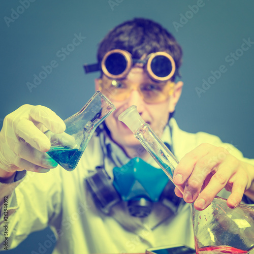 male scientist in a research laboratory, holding a glass flask with blue liquid