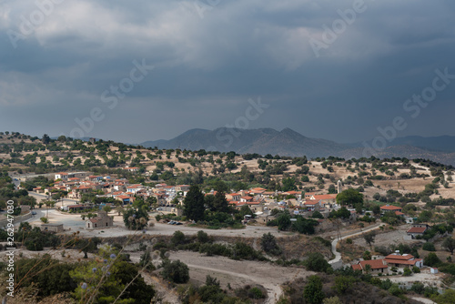 Aerial view of small beautiful village. View of mountains and storm clouds. Summer. © Nikkeero