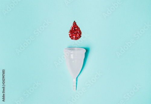 white menstrual cup  with a drop of blood on a blue background photo