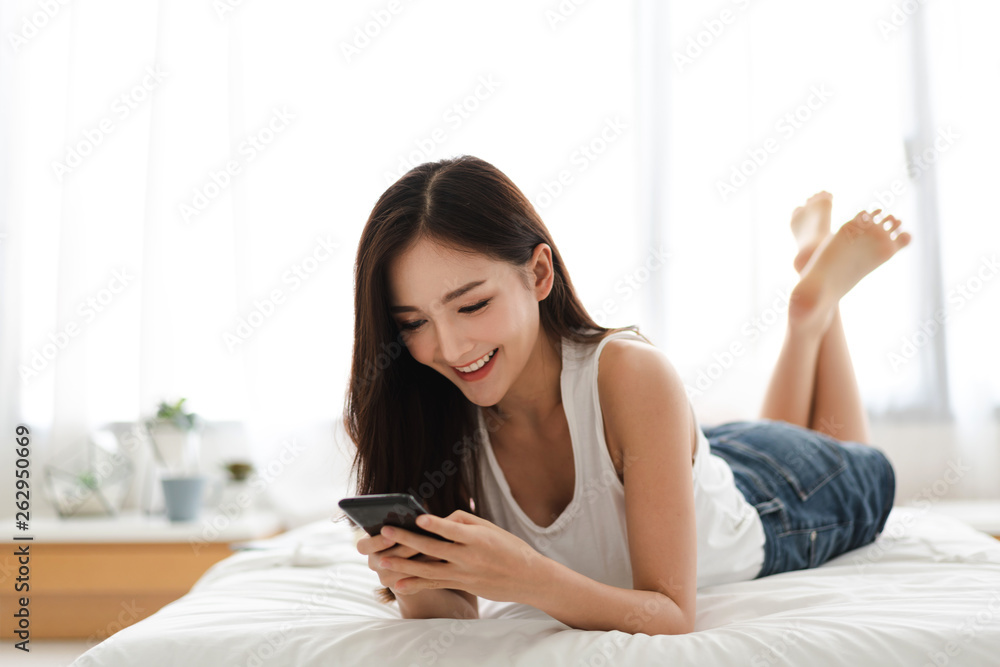 Happy woman relaxing using and talking by smartphone on the bed at home.technology and communication concept Happy woman relaxing using and talking by smartphone on the bed at home.technology and communication concept