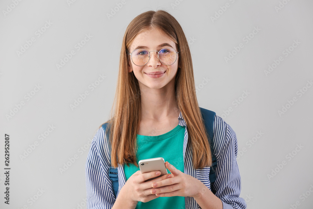 Portrait of cute teenage girl with mobile phone on light background Portrait of cute teenage girl with mobile phone on light background