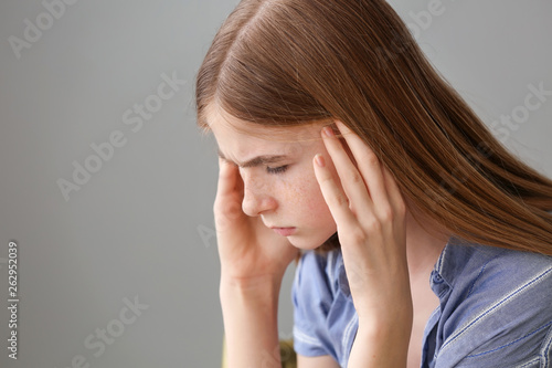 Sad teenage girl on grey ba...