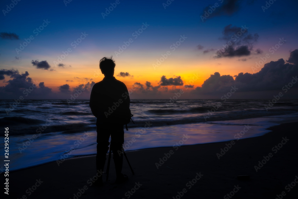 Silhuette men on the beach before sunrise.