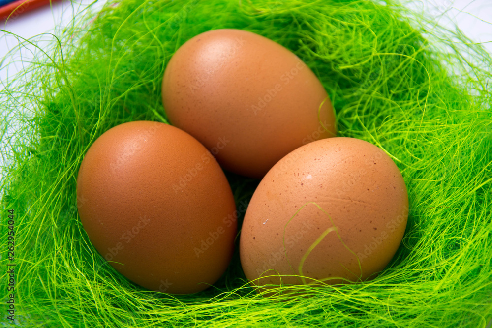 Green nest with chicken beige Easter eggs decoration, close-up, easter concept, holiday tradition, blurred paints, colorful palette on the background, paint equipment on white background Green nest with chicken beige Easter eggs decoration, close-up, easter concept, holiday tradition, blurred paints, colorful palette on the background, paint equipment on white background