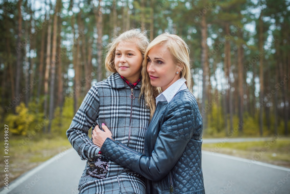 Fototapeta premium Family relationship concept. Woman during the city with the little adorable girl at street outdoors. Mother and daughter 