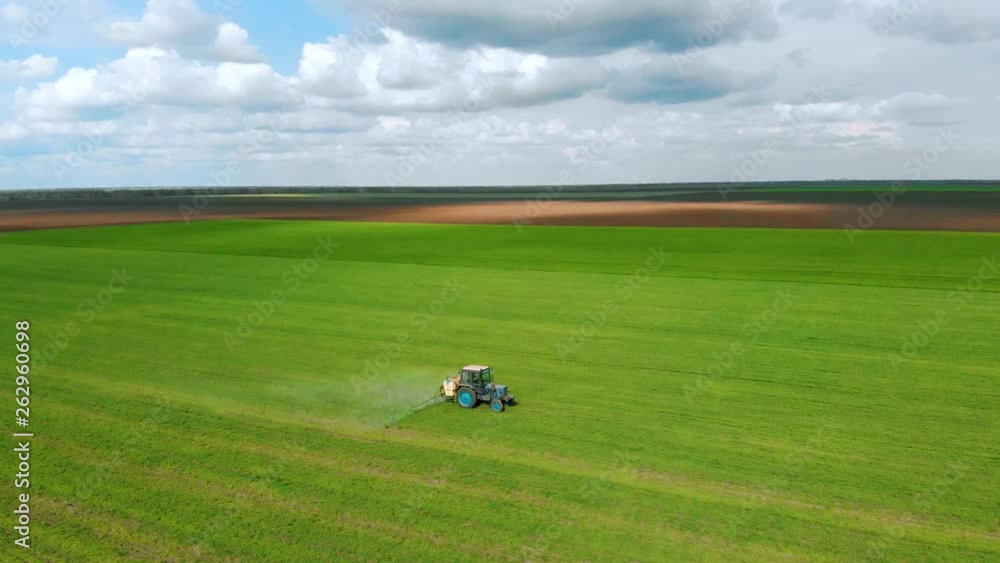 Aerial view of farmer on tractor spraying wheat field for increase yields. Agronomic activities on farm Aerial view of farmer on tractor spraying wheat field for increase yields. Agronomic activities on farm