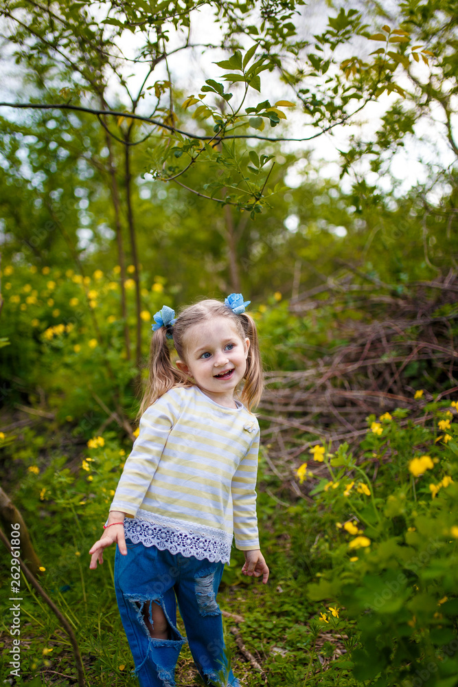 little smiling girl in jeans standing in the garden little smiling girl in jeans standing in the garden