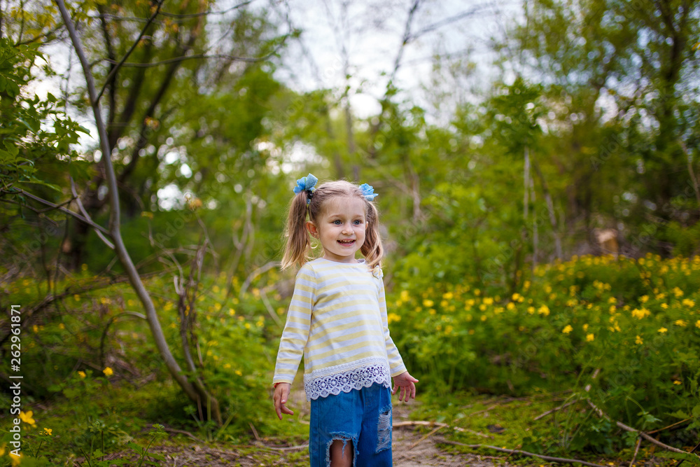 little smiling girl in jeans standing in the park little smiling girl in jeans standing in the park