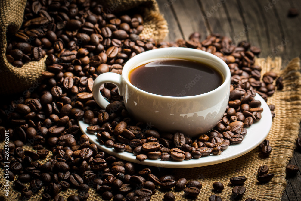 Coffee cup and beans on a rustic background. Coffee Espresso and a piece of cake with a curl. Cup of Coffee and coffee beans on table. Coffee cup and beans on a rustic background. Coffee Espresso and a piece of cake with a curl. Cup of Coffee and coffee beans on table.