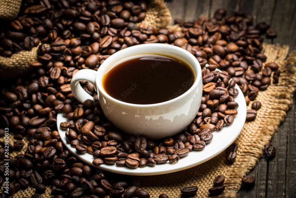 Coffee cup and beans on a rustic background. Coffee Espresso and a piece of cake with a curl. Cup of Coffee and coffee beans on table.