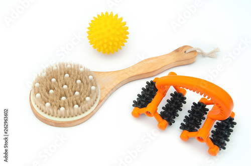 Massage wooden brush, orange roller and yellow ball with spikes close-up for the body on a white background. Anti-cellulite body massagers. Body care at home.