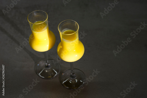 Two glasses of egg liqueur on black texture background photo