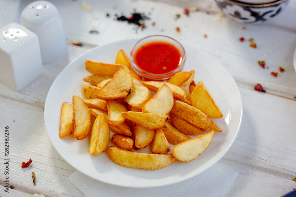 Fried potatoes with red tomato sauce on the white plate. Fried potatoes with red tomato sauce on the white plate.