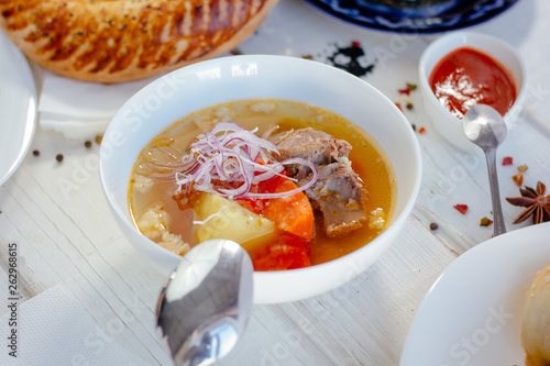 Uzbek chorba - soup from fresh meat and vegetables on white table.