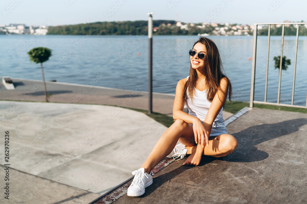 Pretty young brunette girl with long hair relaxing outdoor in the park near lake. Pretty young brunette girl with long hair relaxing outdoor in the park near lake.