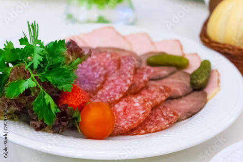 snacks - sausage, ham, tomato, strawberry, pickled cucumbers - on a white plate