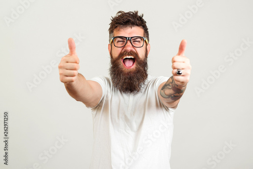 Lucky bearded hipster man over white background. Bearded man wearing glasses. Happy winner. Handsome bearded guy gesturing winner and keeping mouth open. Emotion and gesturing concept. photo