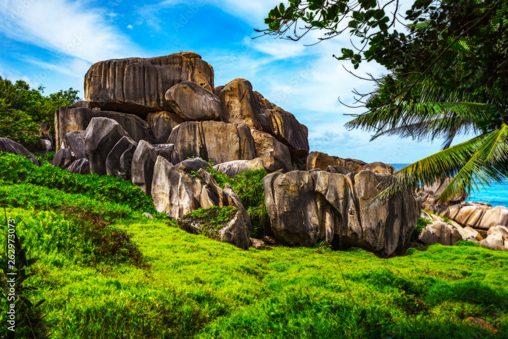 Mighty red granite rocks in lush green grass at anse songe, la digue, seychelles 3