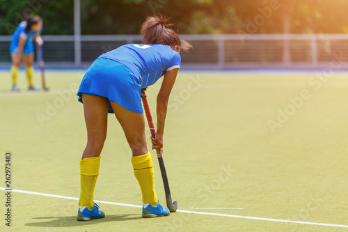 Young female field hockey player with stick on the pitch