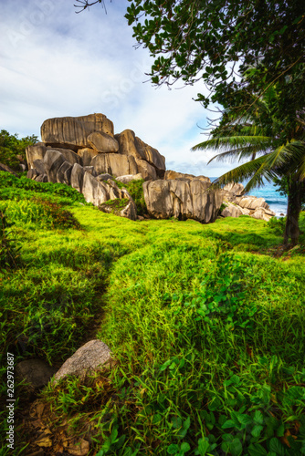 Mighty red granite rocks in lush green grass at anse songe, la digue, seychelles 21