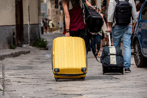 Fototapeta Naklejka Na Ścianę i Meble -  Suitcases with wheels dragged through the streets in the city