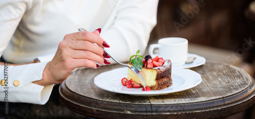 Dessert cake cup of coffee and female hand with fork close up. Piece of cake with red berry. Gourmet recipe food. Cake slice on white plate. Cake with cream delicious dessert. Appetite concept