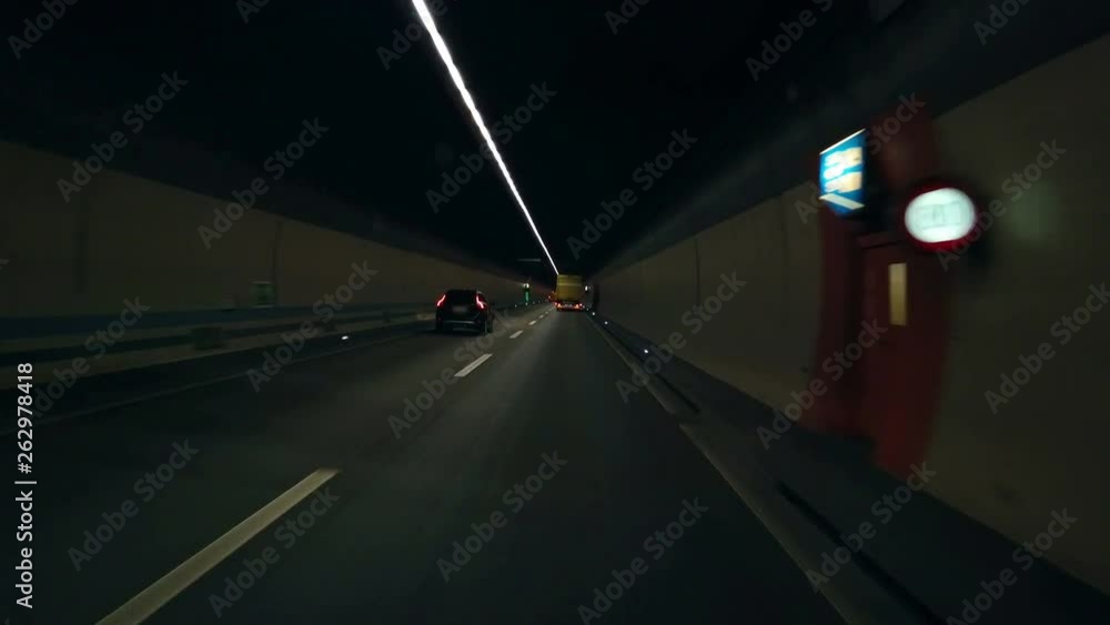 A couple of vehicles are driving on a highway in a tunnel and it looks quite dark. A couple of vehicles are driving on a highway in a tunnel and it looks quite dark.