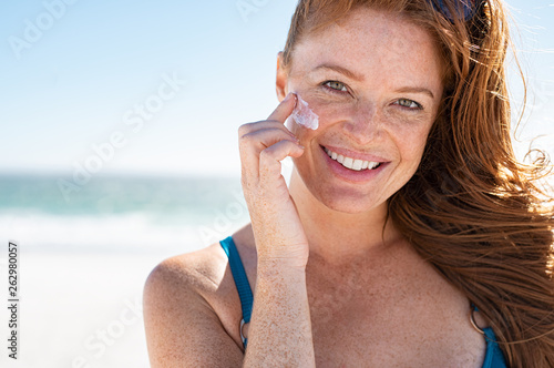 Mature woman applying sunscreen on face