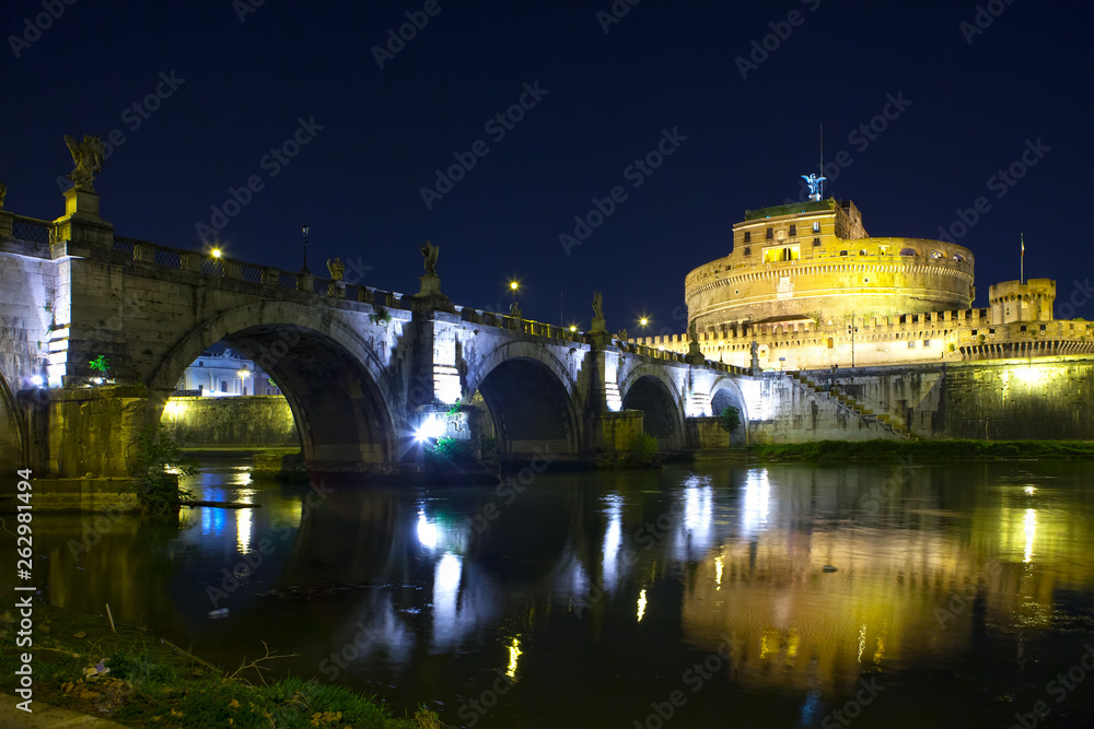 View of the bridge and the Angel Castle at night in the illumination over the Tiber River. Rome. Italy.
