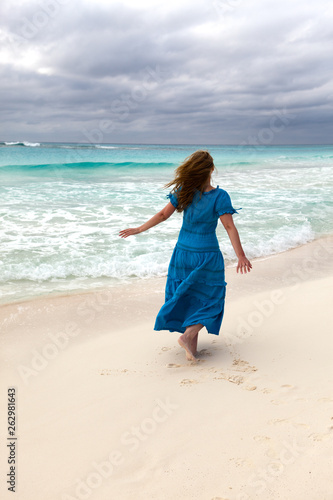 woman in a long blue dress on the stormy sea coast