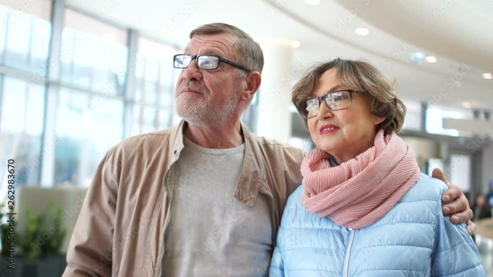 Senior couple at airport. Man and woman talking in the lounge, looking into the distance, waiting for your flight Senior couple at airport. Man and woman talking in the lounge, looking into the distance, waiting for your flight