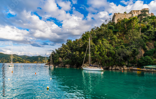 View of castle Brown on the hill and sailboats on water in the spectacular bay of Portofino in Liguria region in Italy