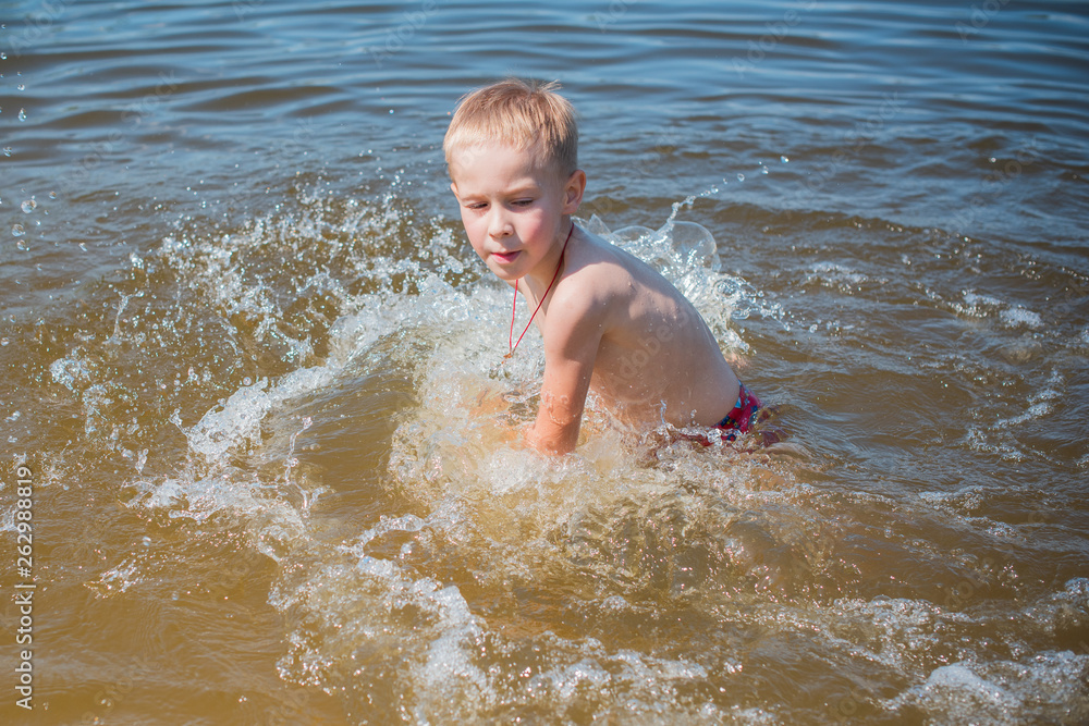 Boy playing on the beach on summer holidays. Children in nature with beautiful sea, sand and blue sky. Happy kids on vacations at seaside in the water Boy playing on the beach on summer holidays. Children in nature with beautiful sea, sand and blue sky. Happy kids on vacations at seaside in the water
