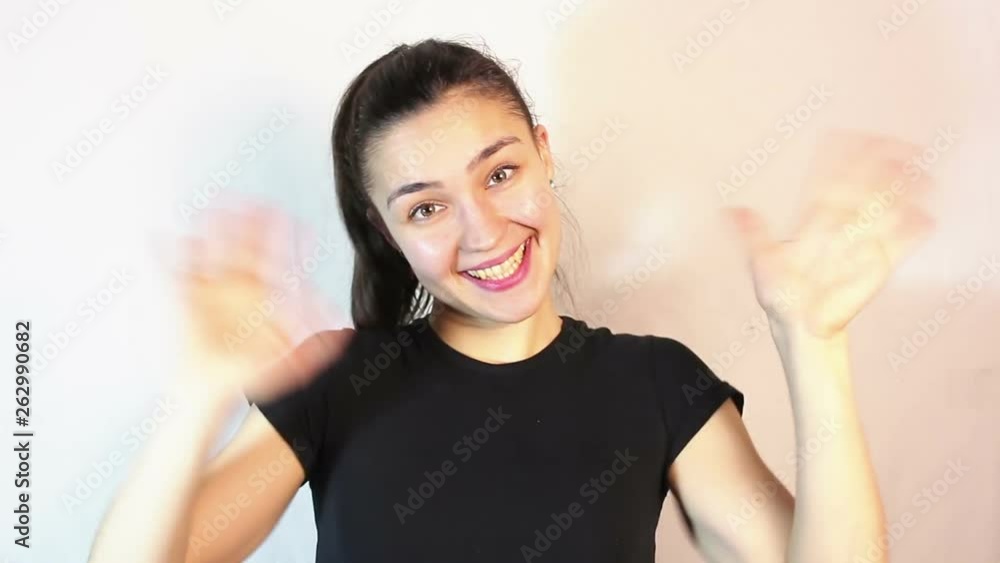 Young beautiful girl looking at the camera waving her arms in greeting.Portrait on a white background. Young beautiful girl looking at the camera waving her arms in greeting.Portrait on a white background.