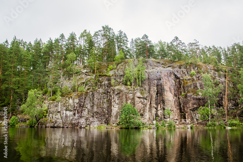 calm lake with reflection of the rock and forest on the shore