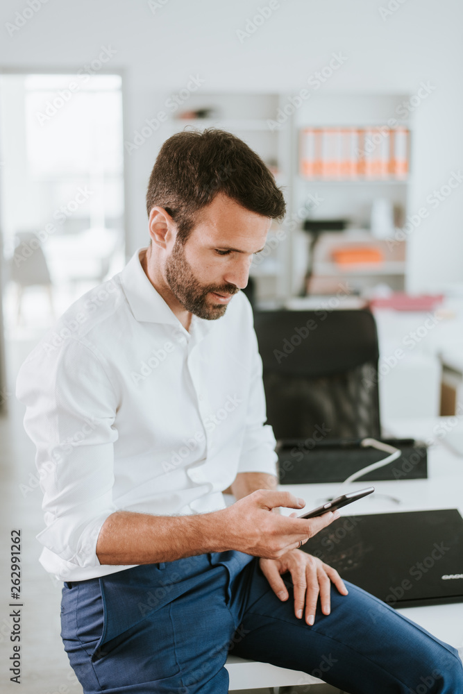 Manager on his phone. Man at work sitting on a desk while talking on the phone. Manager on his phone. Man at work sitting on a desk while talking on the phone.