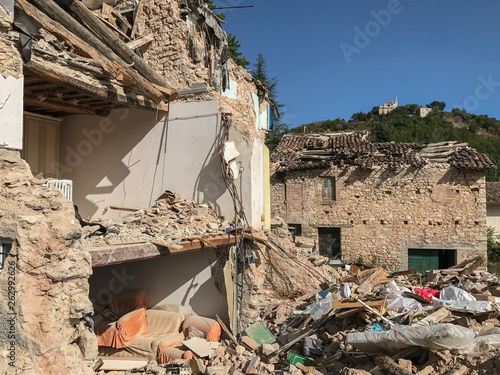 A badly damaged house in rural Italy after an earthquake, the external wall has been destroyed exposing the inside of the house, against a blue sky