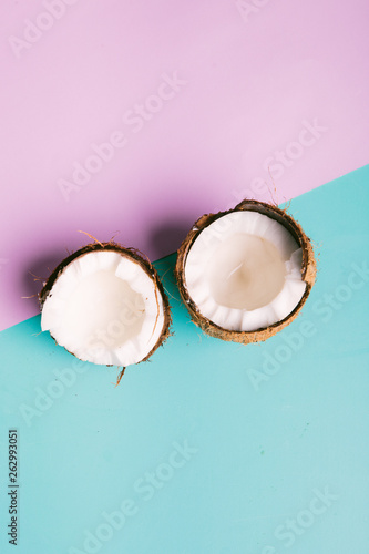 Coconut on a blue and pink background with space for text. Half of coconut on turquoise and pink background. Tropical fruit concept.