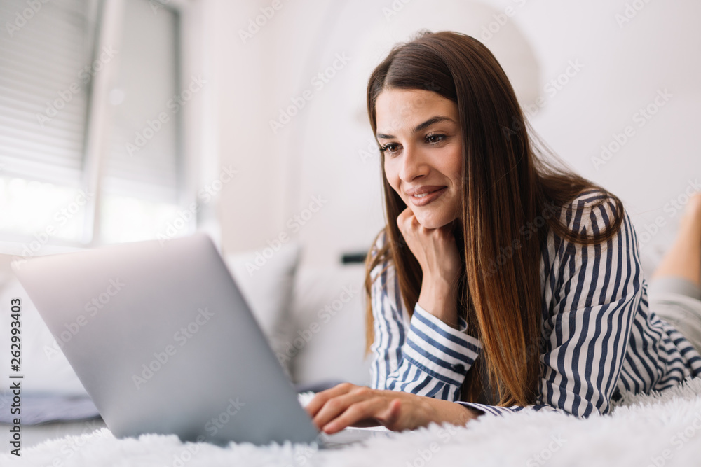 Girl on her laptop at home. Woman using her laptop while lying down. Young female works from home. Girl on her laptop at home. Woman using her laptop while lying down. Young female works from home.