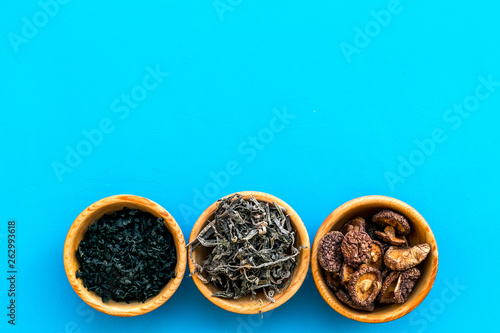 Chinese and Jupanese food cooking with mushrooms, spices, weeds in bowl on blue background top view copy space