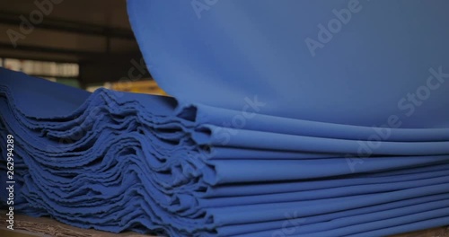 The garment factory takes a sample of a roll of blue fabric checking the quality of the roll checking on the machine the roll of fabric is unwound fully. Concept of: Checking quality, New fabric.