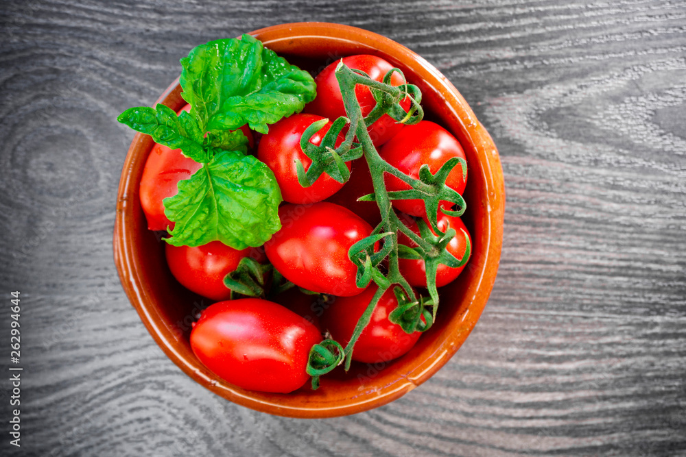 Fresh tomatoes and basil in a plate on a dark background